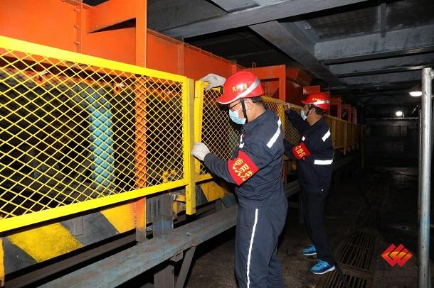 图为职工为皮带输送系统安装防护网