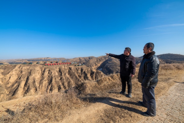 图为高西沟村党支部副书记高利东正在和村民一起瞭望远处的光伏板