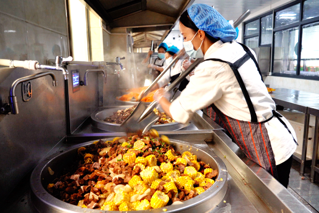 图为食堂师傅正在精心烹制午餐